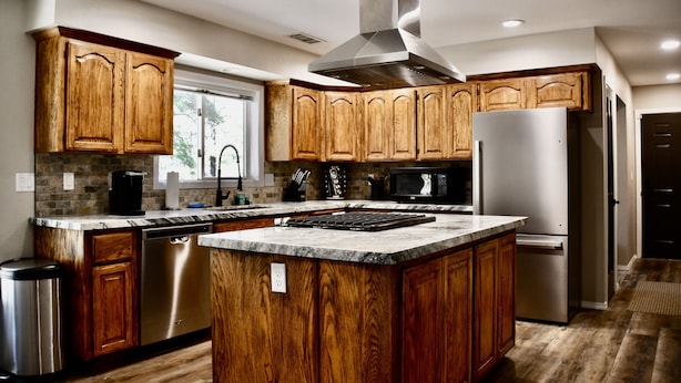 A modern kitchen with wooden cabinets, stainless steel appliances, and a large island.
