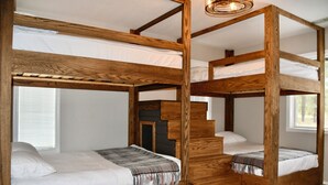 A bunk bed room with wooden frames and white bedding.