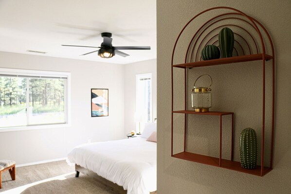 Un dormitorio con cama, mesita de noche, ventana y ventilador de techo.