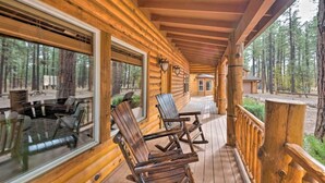 Una cabaña de madera con porche, ventanas amplias y un comedor con mesas al aire libre.