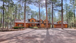 Una cabaña de troncos grande con varias habitaciones, rodeada de un bosque.