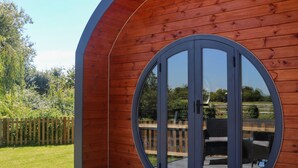Una cabaña de madera con un ventanal circular y una terraza de madera.
