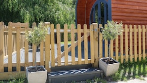 Una cerca de madera con un letrero que dice "Willow Pod" y un pequeño jardín con plantas en macetas.