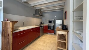 Une cuisine moderne avec des meubles de couleur rouge, un îlot central en bois, des appareils électroménagers en acier inoxydable et un four encastré.