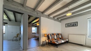 Une pièce spacieuse avec des poutres apparentes, un canapé, un radiateur et un tableau encadré au mur.