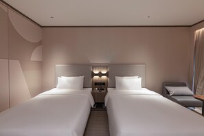 A hotel room with two beds, a nightstand, a chair, and a wall-mounted lamp. - Hanting Hotel (Changzhou)