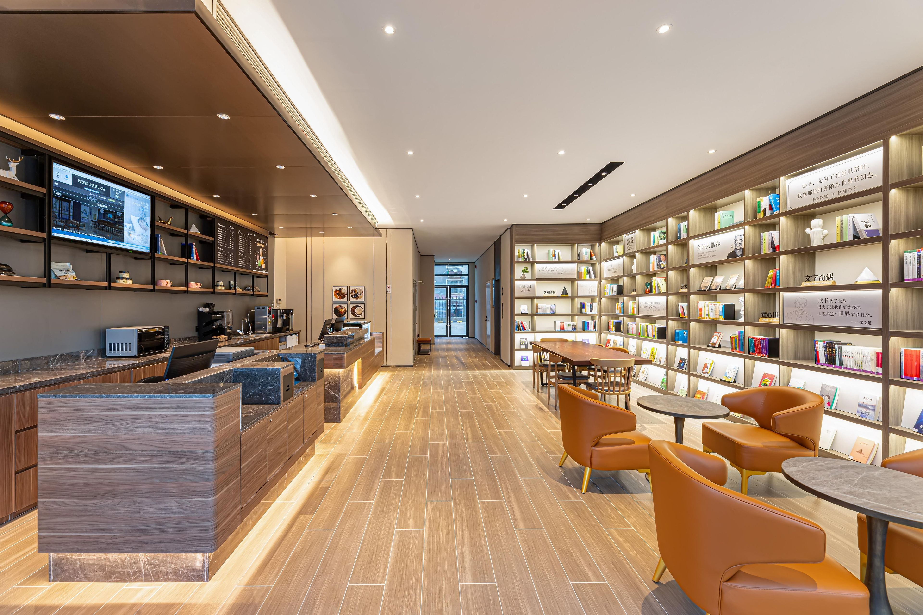 A modern library with a reception desk, seating area, and bookshelves.