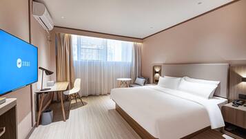 A hotel room with a bed, desk, chair, TV, and a window with curtains.