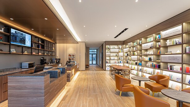 Et moderne bibliotek med en lang træreol, en reception og behagelige siddeområder.