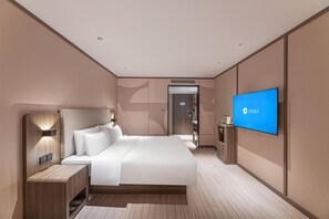 A modern hotel room with a large bed, a TV mounted on the wall, and a small desk with a mirror. - Hanting Hotel (Changzhou)