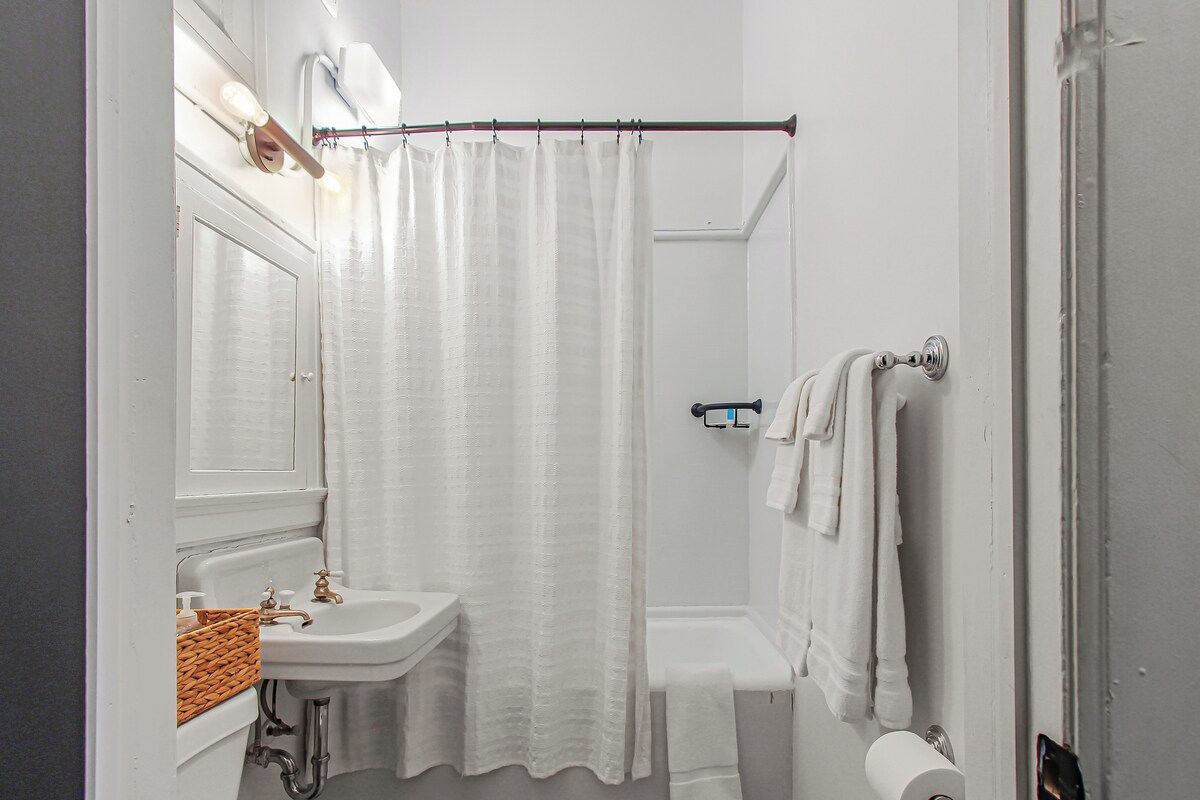 Ein Badezimmer mit weißem Waschbecken, einer Duschvorhang, einem Handtuchhalter und einer Toilette.