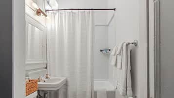 Ein Badezimmer mit weißem Waschbecken, einer Duschvorhang, einem Handtuchhalter und einer Toilette.
