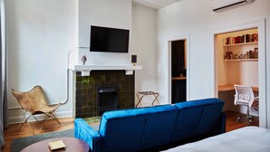 A modern living room with a fireplace, a flat-screen TV, a blue sofa, and a bookshelf. - Walkable to Huntington Center, Fifth-Third Field and the Convention Center! (Toledo)
