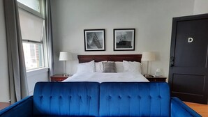 A hotel room with a large bed, two bedside tables, a blue sofa, and two framed pictures on the wall. - EZ Check-in and Check-Out, Perfect for a Night Downtown! (Toledo)