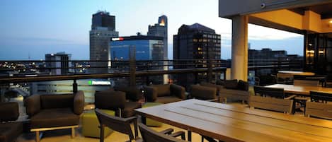 Una terraza en la azotea con mobiliario exterior y vistas a la ciudad.