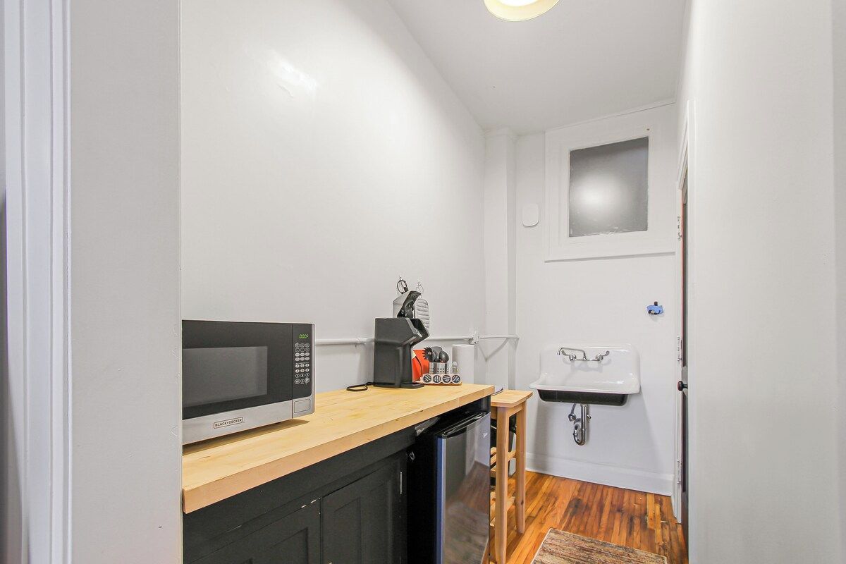 A compact kitchenette with a microwave, coffee maker, and sink.