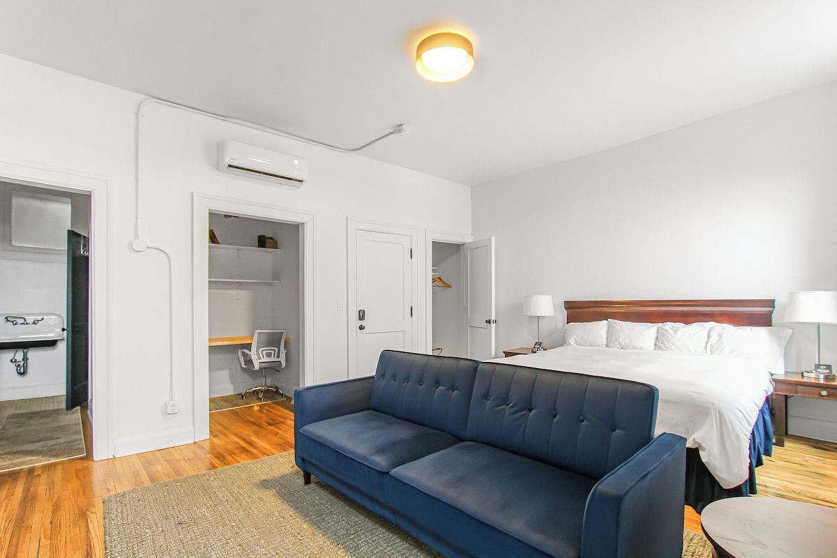 Una habitación de hotel con una cama, un sofá azul, un escritorio y una silla.