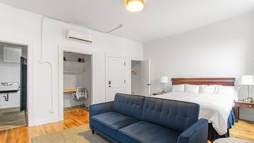Una habitación de hotel con una cama, un sofá azul, un escritorio y una silla.