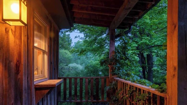A wooden deck with a railing, a window, and a view of a forest. - Creekside Cabin with Hot Tub & Wood-Burning Stove (Lanesville)