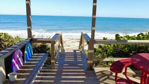 Eine Holzterrasse führt zu einem Strand mit freiem Blick auf das Meer.