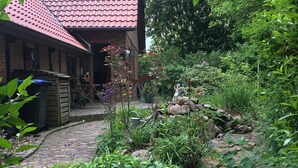 Un jardín con una casa de ladrillo, un sendero de piedra y diversas plantas.