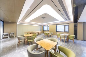 A modern conference room with a high ceiling, large windows, and a mix of wooden and upholstered chairs.