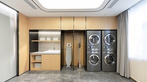 A modern bathroom with a sink, toilet, and stacked washer-dryer units. - Ji Hotel (Taiyuan)