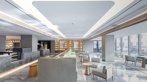 A modern hotel lobby with a reception desk, seating area, and a display of items. - Ji Hotel (Taiyuan)