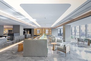 Un hall d’hôtel moderne comprenant un comptoir d’accueil, un espace salon et une vitrine exposant divers objets.