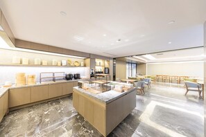 Une cuisine moderne avec un sol en marbre, des meubles en bois et un îlot central doté de divers ustensiles de cuisine.