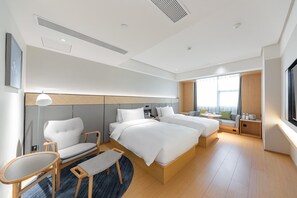 A modern hotel room with a large bed, two bedside tables, a seating area with a chair and bench, a small table, and a large window providing natural light. - Ji Hotel (Taiyuan)