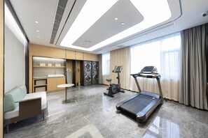A hotel room with a treadmill, a seating area, a washing machine, and a vanity with a mirror. - Ji Hotel (Taiyuan)