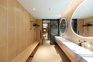 A modern bathroom with wooden paneling, a bench, a mirror with a light, and a sink with a soap dispenser. - Ji Hotel (Taiyuan)