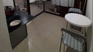 A compact kitchen with a sink, a small countertop, a window with curtains, and a dining area with a table and chairs. - ESTUDIO EN CARTAGENA CERCA AL MAR 202 (Cartagena)