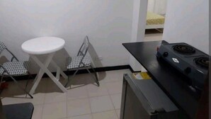 A small kitchenette with a stove, a chair, and a table. - ESTUDIO EN CARTAGENA CERCA AL MAR 202 (Cartagena)