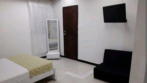 A small, sparsely furnished room with a bed, a chair, a wardrobe, and a television. - ESTUDIO EN CARTAGENA CERCA AL MAR 202 (Cartagena)