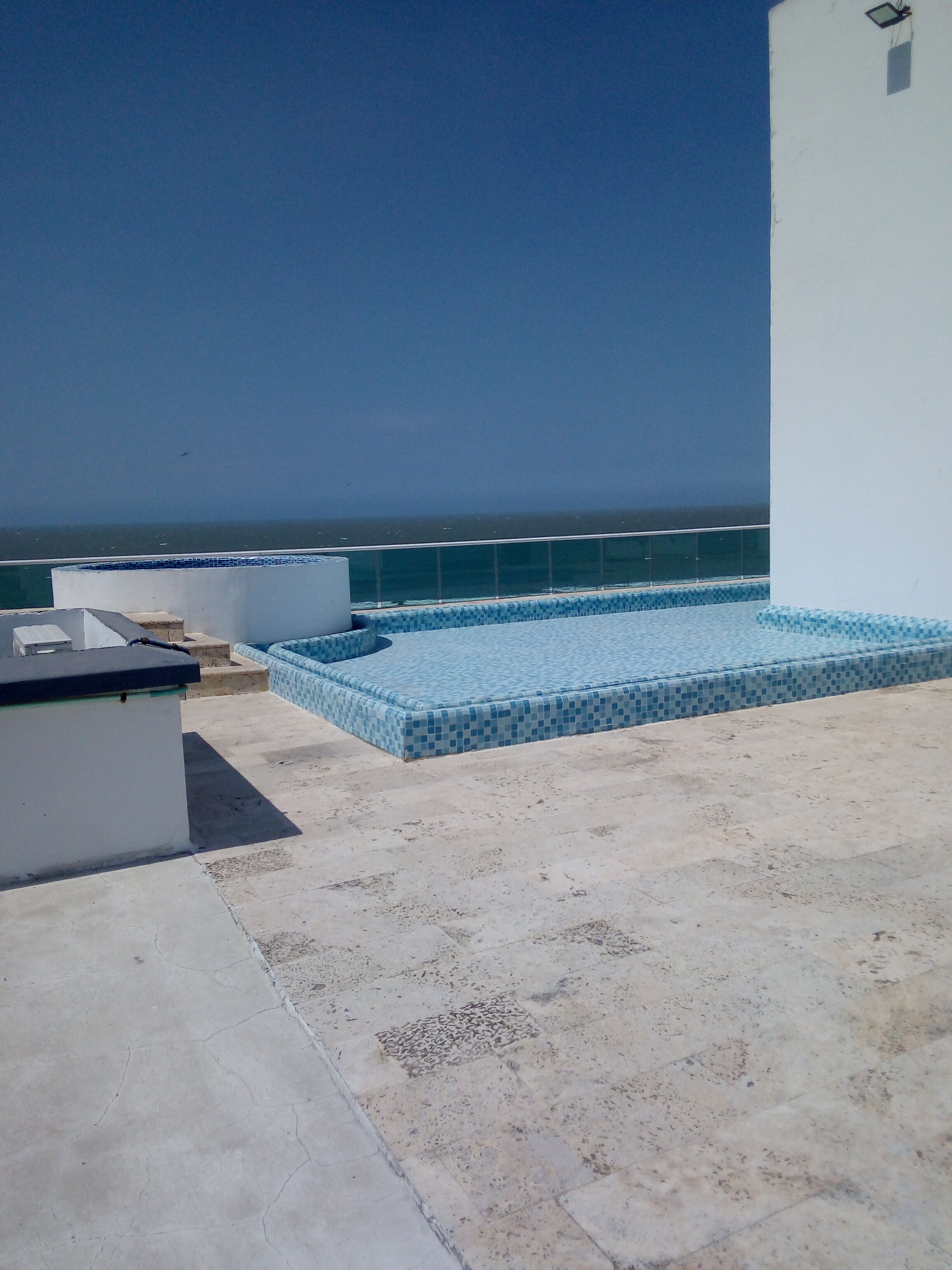 A rooftop terrace with a pool and a view of the sea.
