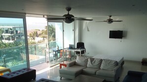 A modern living room with a sectional sofa, a coffee table, and a TV mounted on the wall. There is a balcony with a glass door leading outside. - apartment- suits 1 to 14 people (Cartagena)