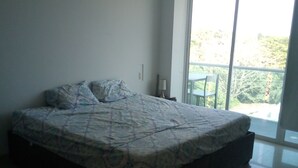 A bedroom with a large bed, a nightstand, and a window with a view of greenery. - apartment- suits 1 to 14 people (Cartagena)