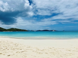 A beach with clear turquoise water, white sand, and distant hills. - Villa Rosa- Newly Renovated 1 Bedroom Condo - Sleeps 4, Great View & 2 Pools (St. Thomas)