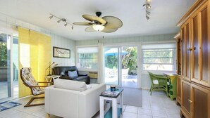 Ein geräumiges Wohnzimmer mit einem weißen Sofa, einem Deckenventilator und einem Essbereich mit Tisch und Stühlen.