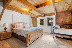 Un dormitorio con dos camas de madera, una mesita de noche con lámpara y una puerta que da al exterior.