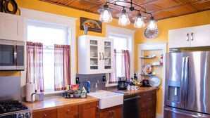 Une cuisine avec des meubles en bois, des appareils électroménagers en acier inoxydable et une fenêtre avec des rideaux.