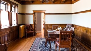 Une salle à manger aux murs lambrés, ornée d’un lustre et dont la table est dressée pour quatre personnes.