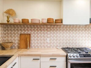 A kitchen with a geometric patterned backsplash, a gas stove, and a wooden cabinet.