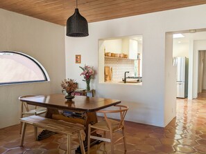 Enjoy meals in this cozy dining area with a wooden table, comfortable chairs, and a stylish pendant light.
