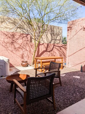 Relax in this serene outdoor seating area with a wooden table and two wicker chairs.
