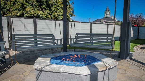 Un espace aménagé avec un foyer, des bancs et un muret en pierre.