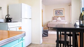 Une cuisine de taille réduite équipée d’une cuisinière, d’un réfrigérateur et d’un coin repas avec une table et des chaises.