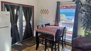Zona pranzo con tavolo e sedie, frigorifero, pianta e vista all'esterno.